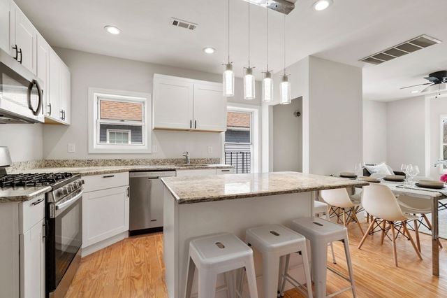 a kitchen with granite countertop a sink chairs and cabinets