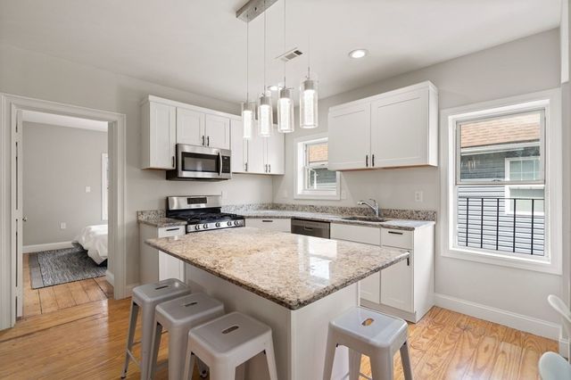 a kitchen with kitchen island granite countertop a stove sink microwave and cabinets