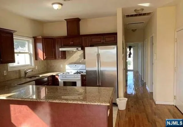 a kitchen with stainless steel appliances granite countertop a sink a stove and a refrigerator