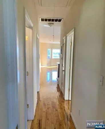 a view of a hallway with wooden floor and a cabinet