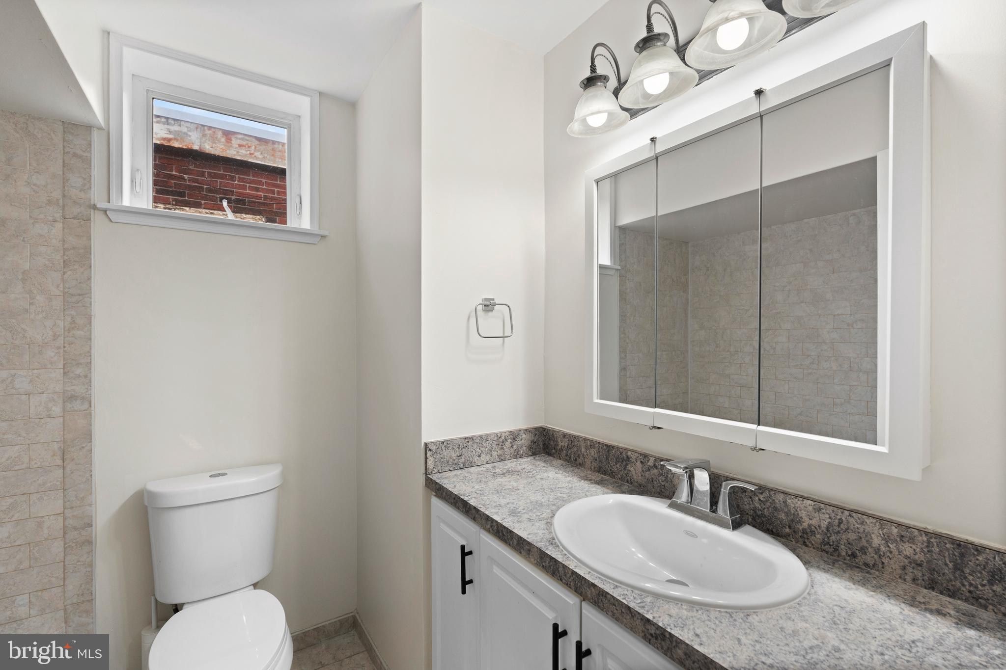 619 South 42nd Street Philadelphia, PA 19104 - Photo 18 of 30 a bathroom with a granite countertop toilet a sink and mirror