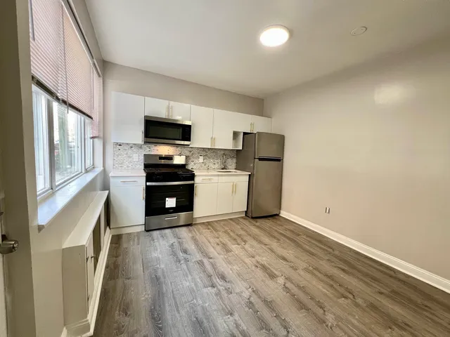 a kitchen with granite countertop a refrigerator and a stove top oven