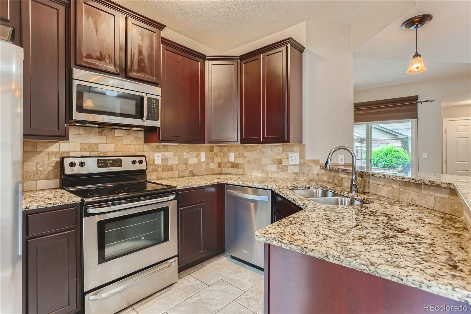 6478 Silver Mesa Drive, Unit E Highlands Ranch, CO 80130 - Photo 11 of 34 a kitchen with stainless steel appliances granite countertop a stove microwave and sink