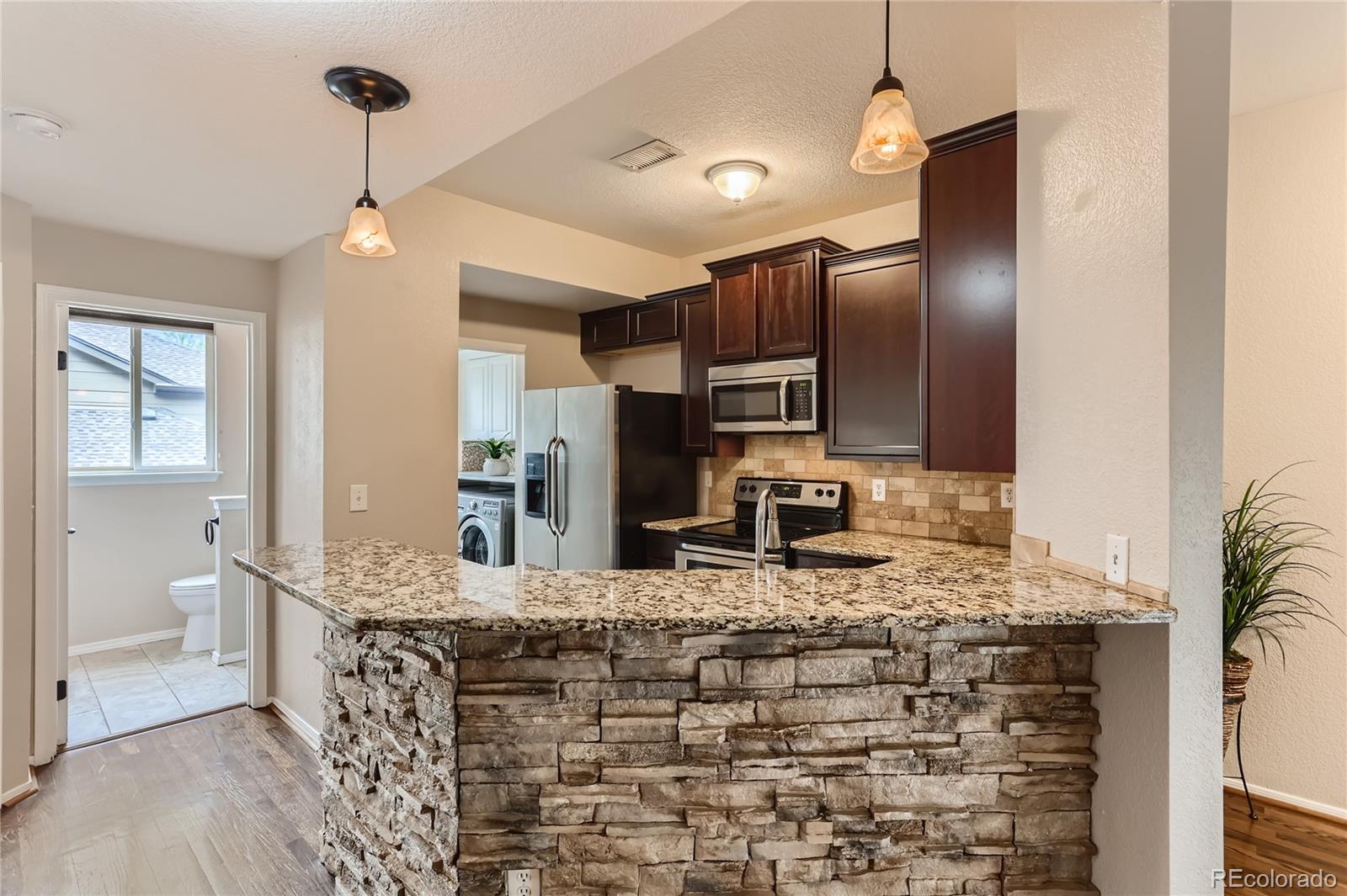 6478 Silver Mesa Drive, Unit E Highlands Ranch, CO 80130 - Photo 13 of 34 a large kitchen with kitchen island granite countertop a sink cabinets and stainless steel appliances