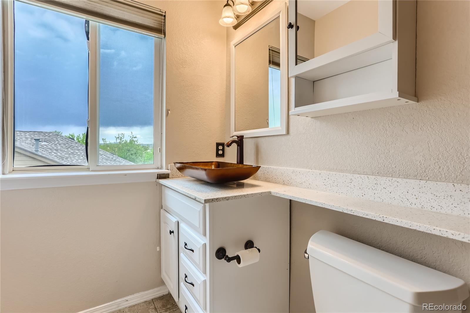 6478 Silver Mesa Drive, Unit E Highlands Ranch, CO 80130 - Photo 24 of 34 a bathroom with a sink a toilet and a window