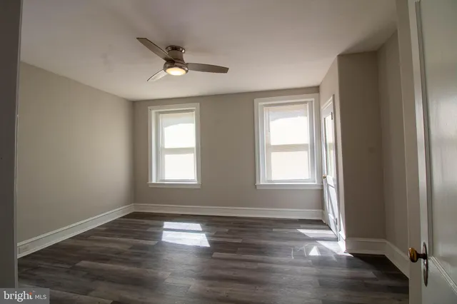 a view of empty room with wooden floor and fan