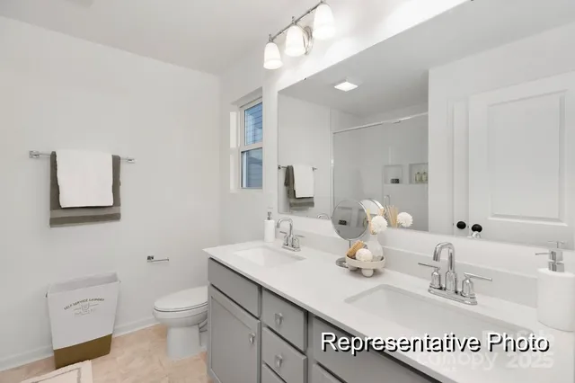 a bathroom with a toilet a double vanity sink and a mirror