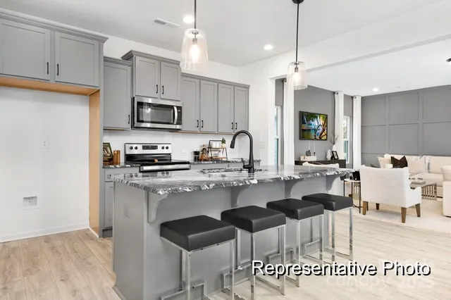a kitchen with kitchen island granite countertop a sink cabinets and stainless steel appliances