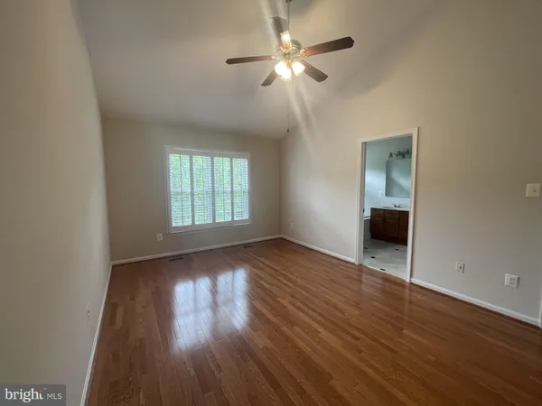 an empty room with wooden floor chandelier fan and windows