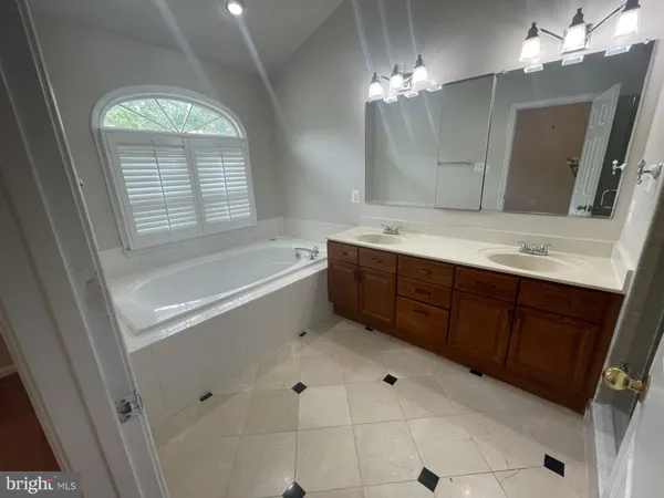 a bathroom with a tub sink and mirror