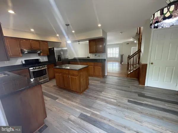 a kitchen with stainless steel appliances kitchen island granite countertop a stove a sink and a microwave