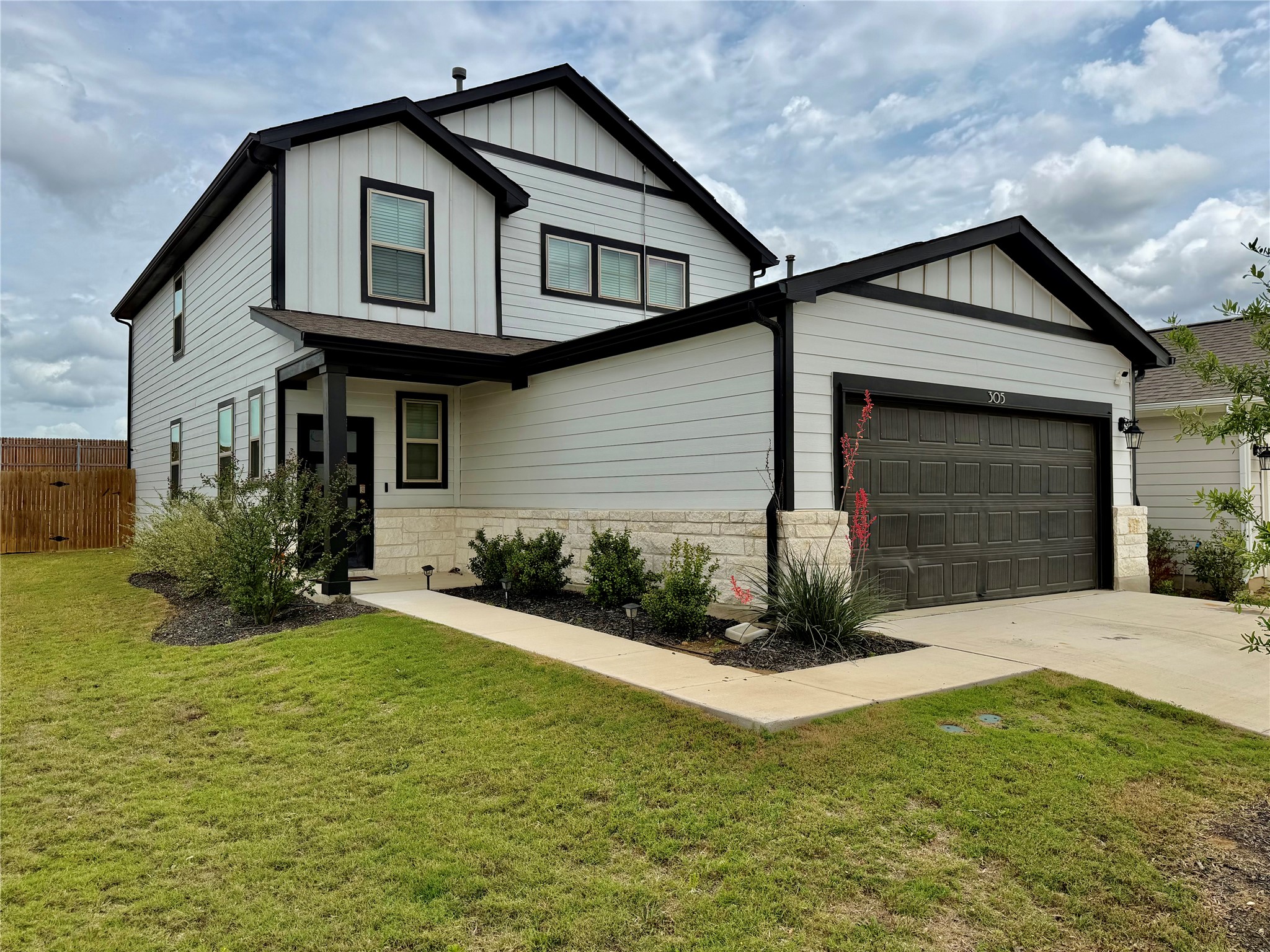 Contemporary two-story residence featuring light horizontal siding with dark trim accents, a two-car garage with a panel door, and a covered entry