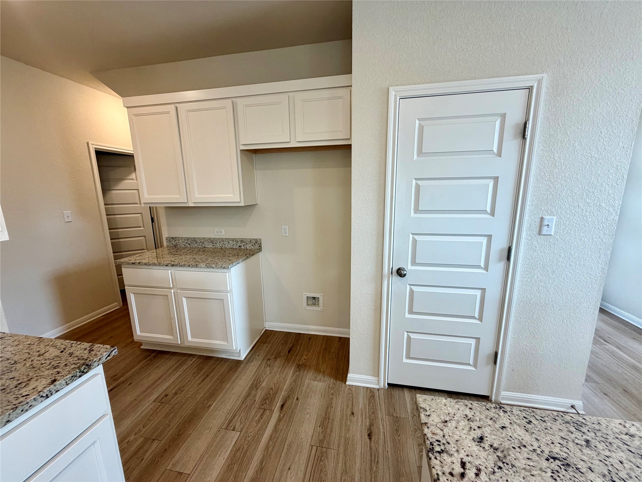 305 Tolo Drive Elgin, TX 78621 - Photo 11 of 27 Kitchen area featuring light wood-finish flooring, white shaker-style cabinetry, and speckled countertops
