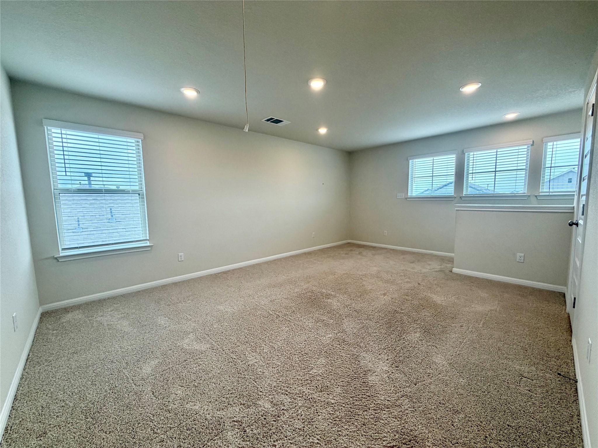 305 Tolo Drive Elgin, TX 78621 - Photo 18 of 27 Spacious room featuring neutral carpeting, recessed ceiling lighting, multiple windows with blinds, and light-toned wall finishes
