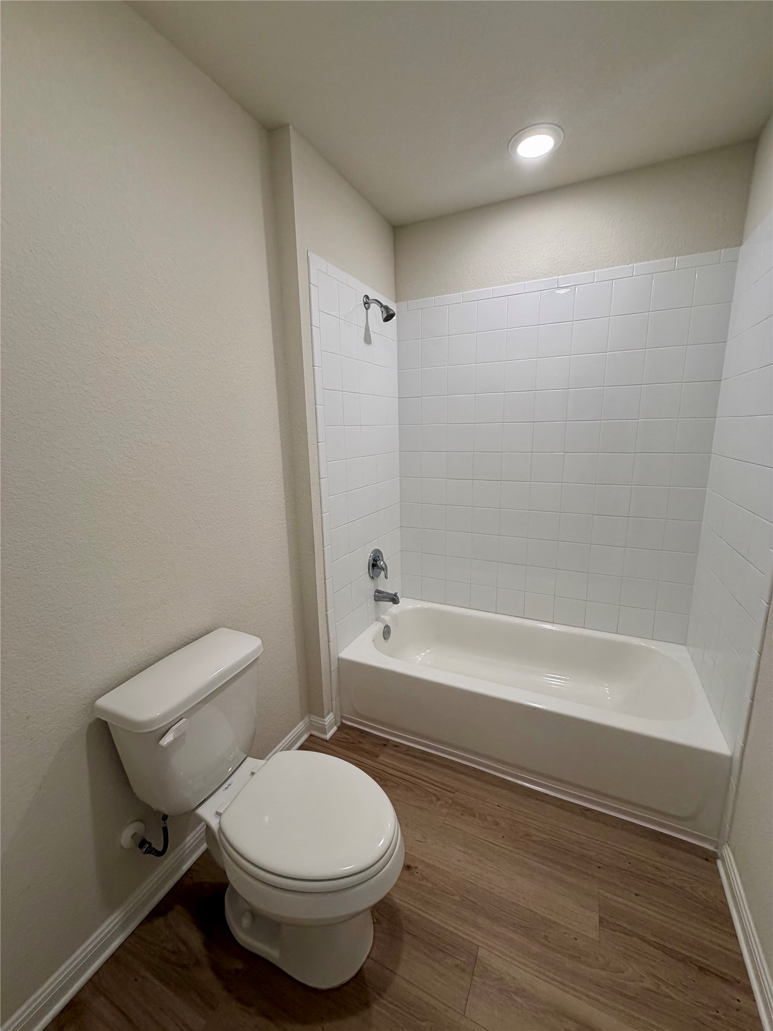 305 Tolo Drive Elgin, TX 78621 - Photo 24 of 27 Bathroom featuring a white bathtub, ceramic tile surround, chrome fixtures, and wood-finish flooring