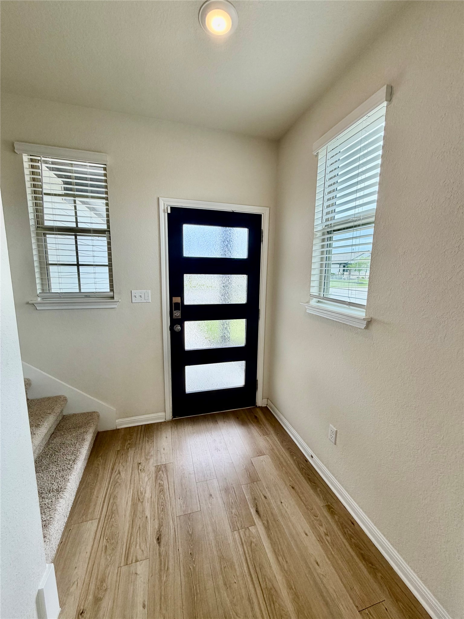 305 Tolo Drive Elgin, TX 78621 - Photo 4 of 27 Entryway featuring wood-finish flooring, a contemporary front door with frosted glass panels, and a recessed ceiling light