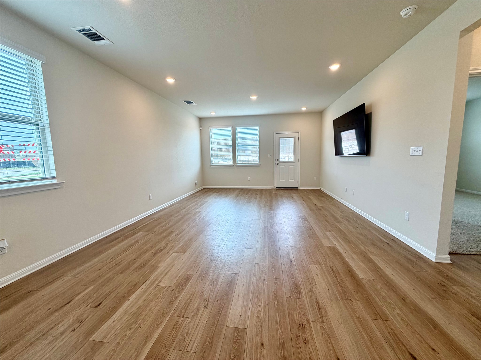305 Tolo Drive Elgin, TX 78621 - Photo 8 of 27 Spacious room featuring wood-finish flooring, recessed ceiling lighting, and multiple windows with blinds