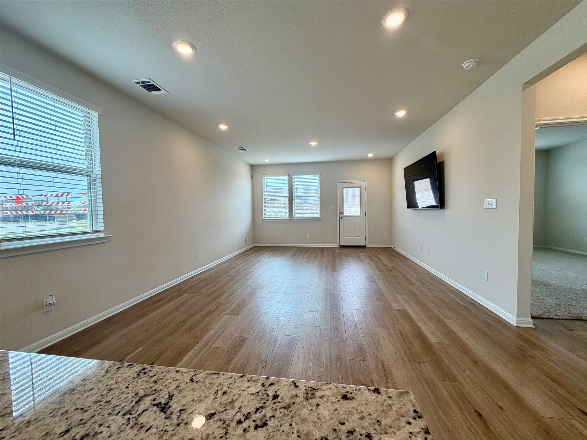 305 Tolo Drive Elgin, TX 78621 - Photo 9 of 27 Open-concept living space with wood-finish flooring, recessed lighting, multiple windows, and a rear exterior door