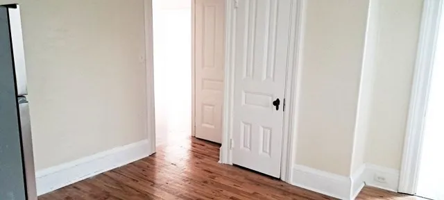 an empty room with wooden floor and a bathroom