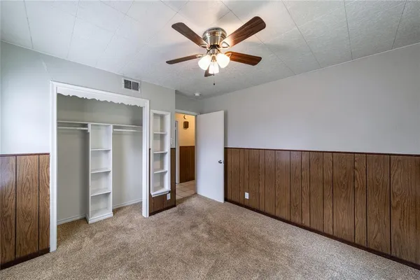 an empty room with closet and ceiling fan