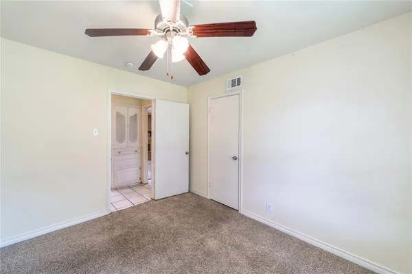 an empty room with chandelier fan and windows