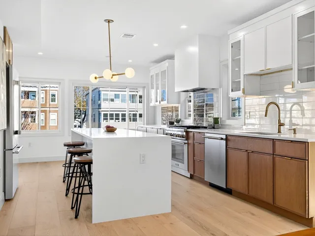 a kitchen with stainless steel appliances granite countertop a stove a sink a refrigerator and white cabinets with wooden floor