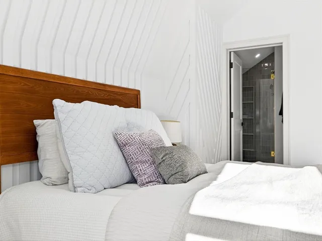 a large white bed sitting in a bedroom and lamp