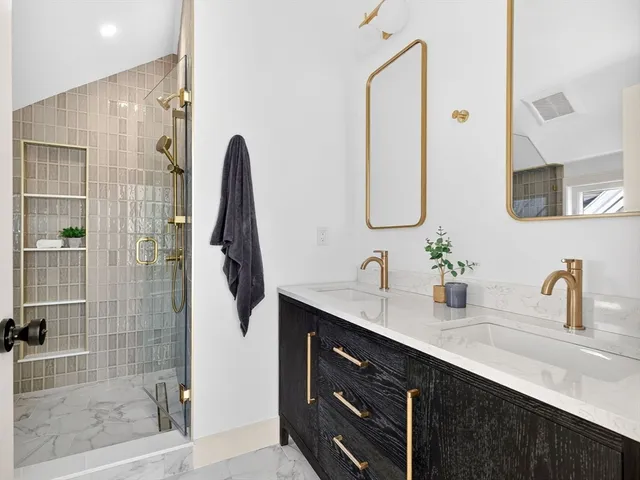 a bathroom with a double vanity sink mirror and shower