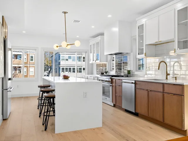 a kitchen with stainless steel appliances granite countertop a stove a sink a refrigerator and white cabinets with wooden floor