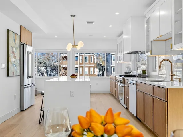 a large kitchen with kitchen island a large counter top space a sink stainless steel appliances and cabinets