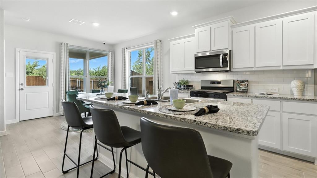 313 Potato Street Keene, TX 76059 - Photo 38 of 40 a kitchen with stainless steel appliances granite countertop a stove a sink a microwave a dining table and chairs