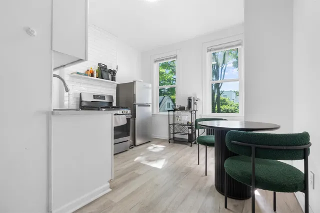 a kitchen with stainless steel appliances a dining table chairs microwave and sink