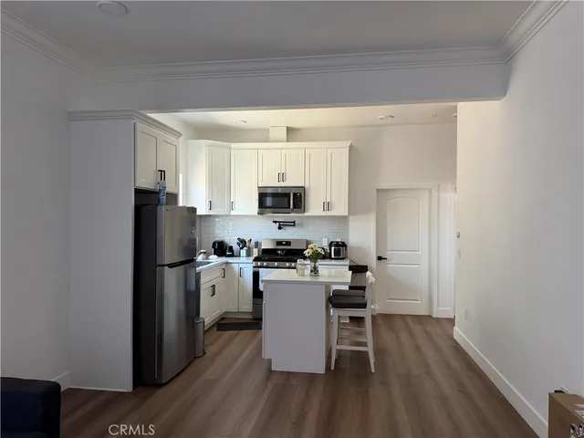 a kitchen with a refrigerator a stove and a wooden floor