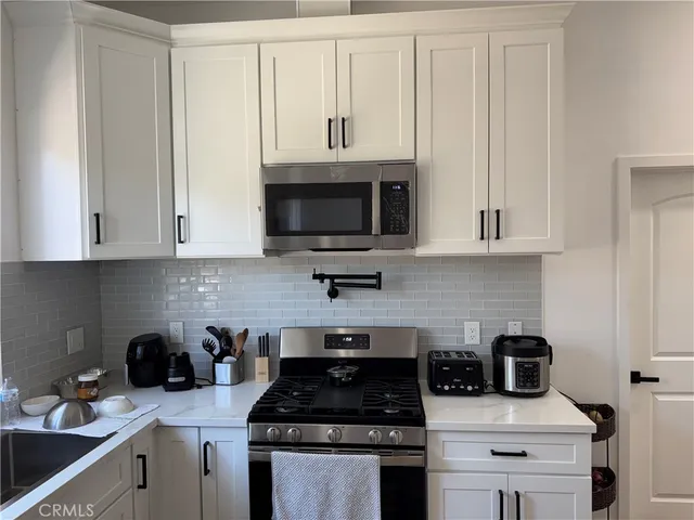 a kitchen with stainless steel appliances granite countertop white cabinets a stove a sink and dishwasher