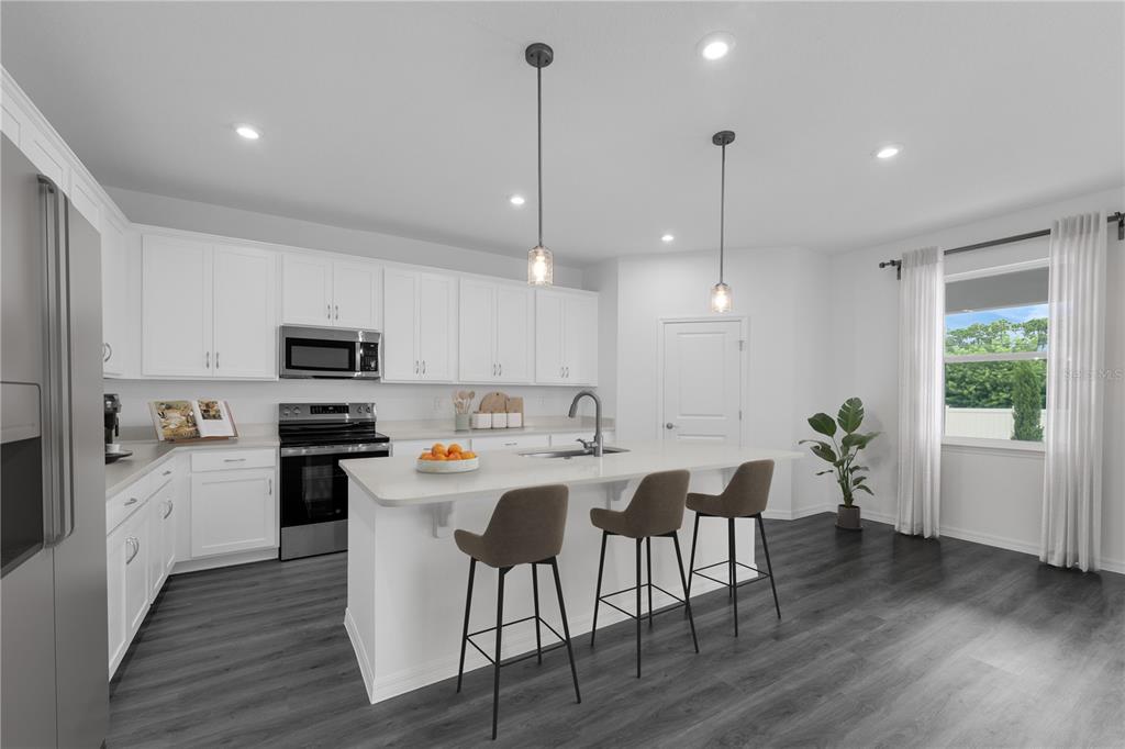 6032 Cliffbow Loop Leesburg, FL 34748 - Photo 9 of 31 a kitchen with stainless steel appliances kitchen island granite countertop a stove a refrigerator a sink a dining table and chairs with wooden floor