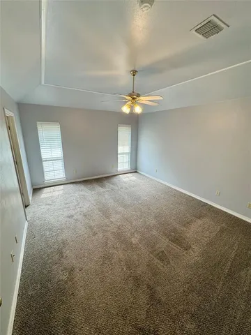 an empty room with a chandelier fan and windows