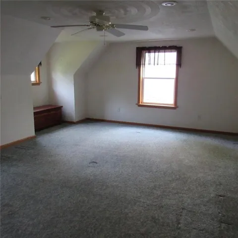 an empty room with windows and ceiling fan