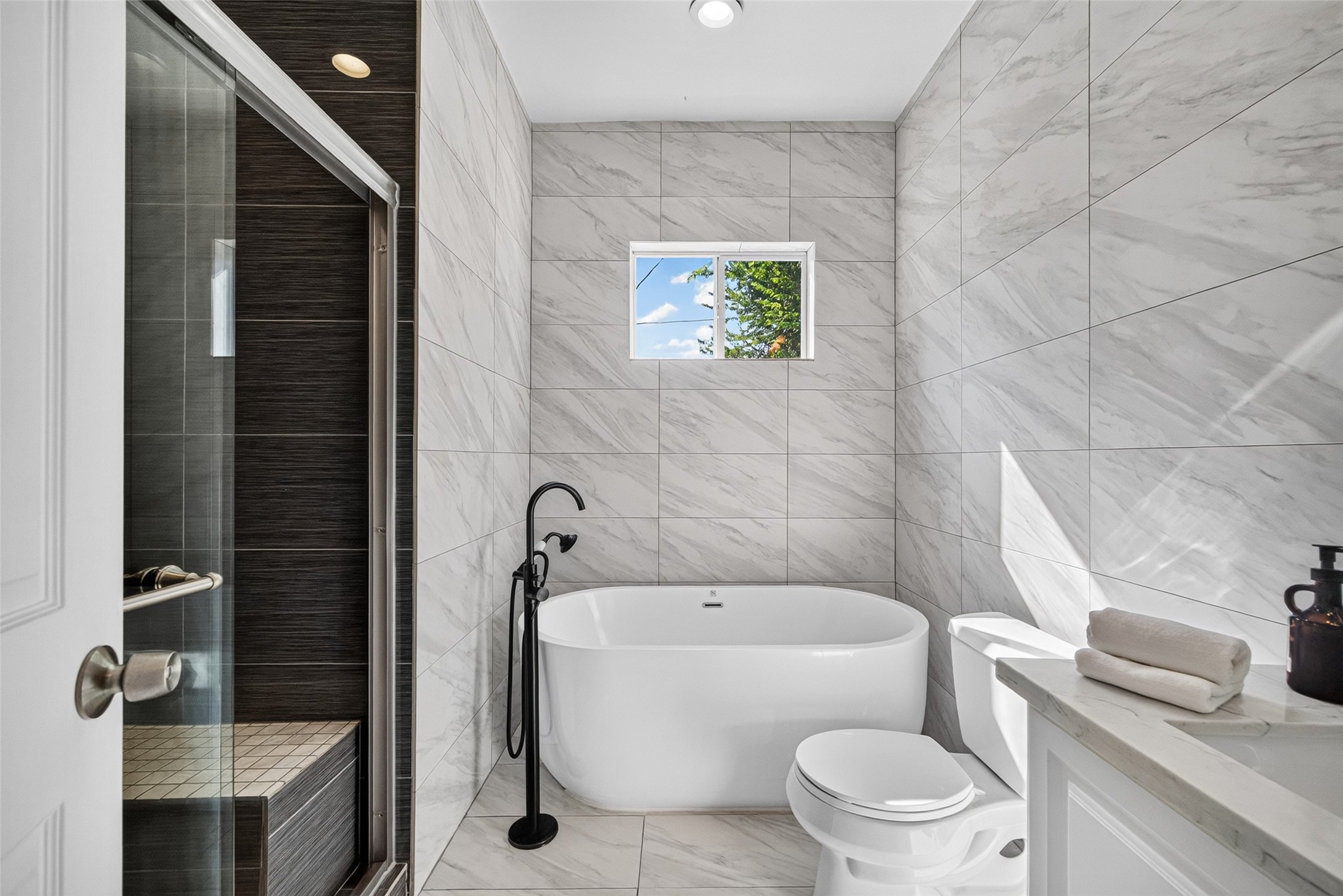 4401 Hain Street Houston, TX 77009 - Photo 14 of 22 Updated bath featuring a freestanding soaking tub, separate glass-enclosed shower, tiled walls and flooring, vanity, and natural light from the window.