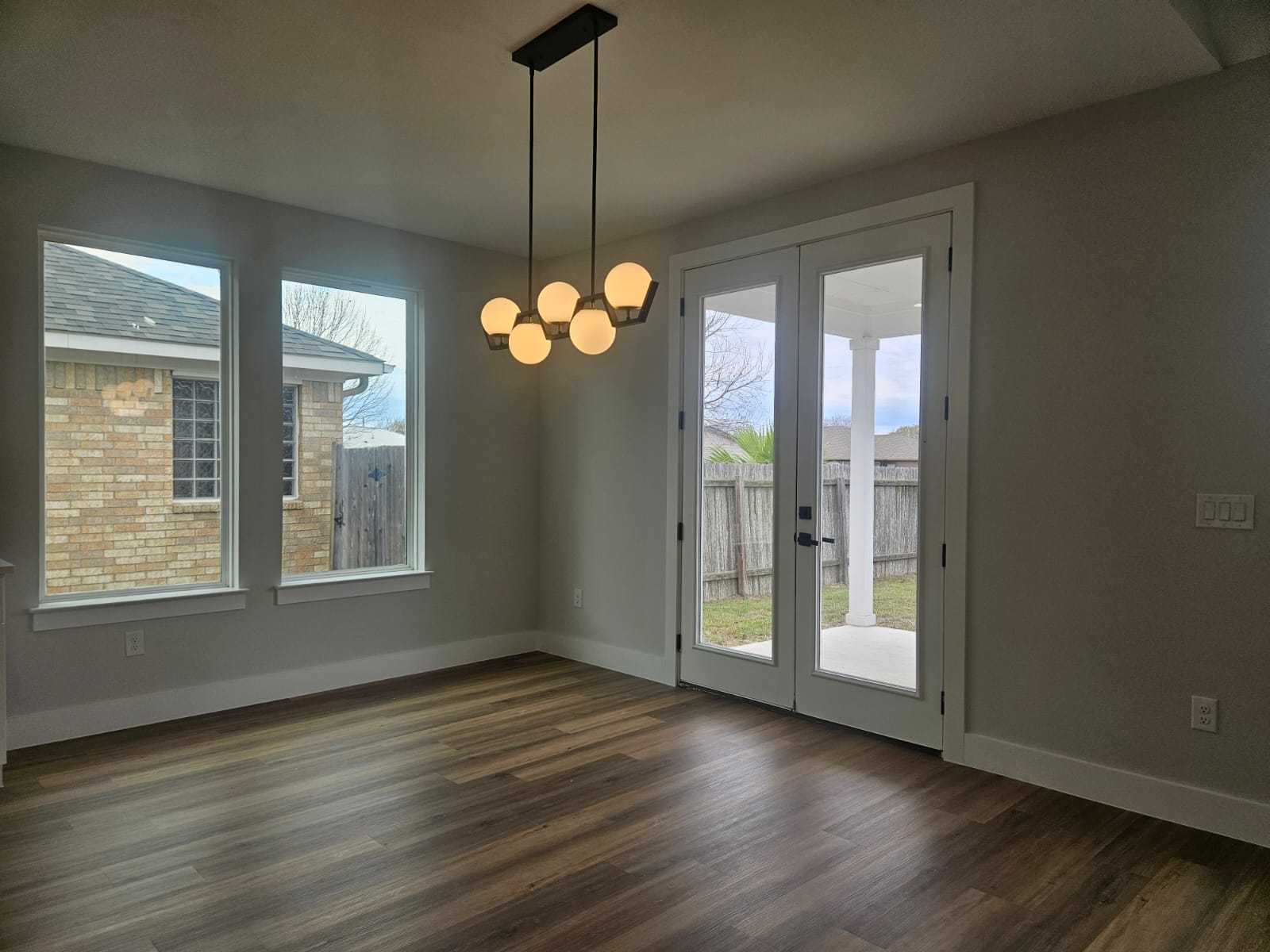 2413 Blue Sky Lane Lockhart, TX 78644 - Photo 15 of 39 Unfurnished dining area with a chandelier, plenty of natural light, dark wood-style floors, and french doors