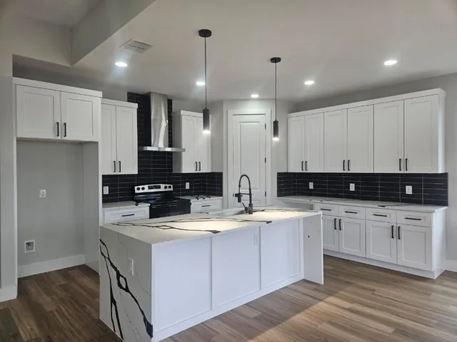 a kitchen with kitchen island granite countertop a sink cabinets and wooden floor