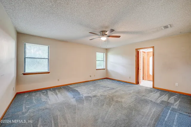 an empty room with windows and ceiling fan