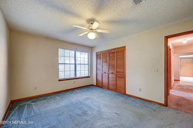 an empty room with chandelier fan and windows