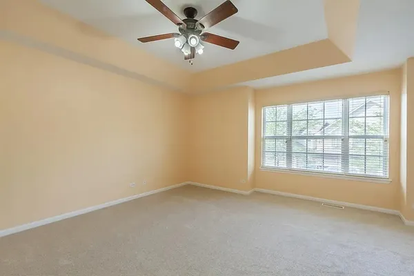 an empty room with chandelier fan and windows