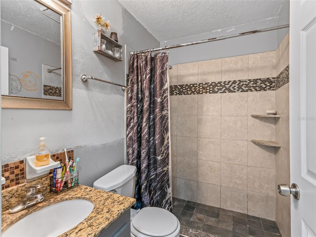 911 Jacaranda Drive Lady Lake, FL 32159 - Photo 14 of 24 a bathroom with a granite countertop sink toilet and shower