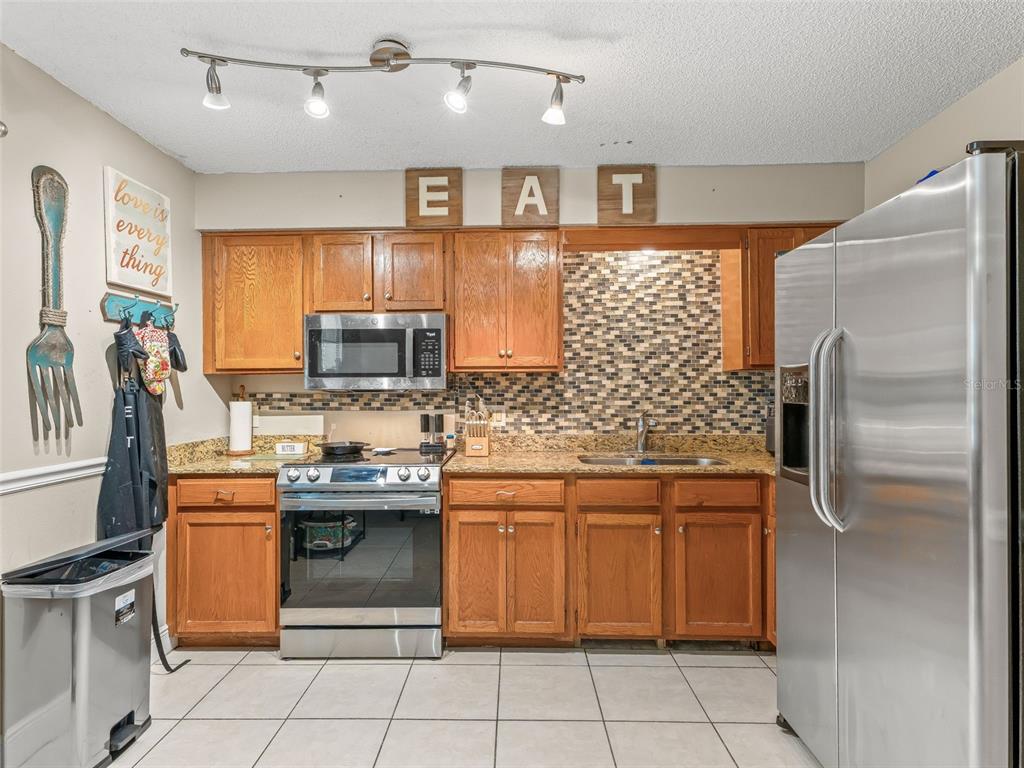 911 Jacaranda Drive Lady Lake, FL 32159 - Photo 7 of 24 a kitchen with stainless steel appliances granite countertop a sink stove and refrigerator