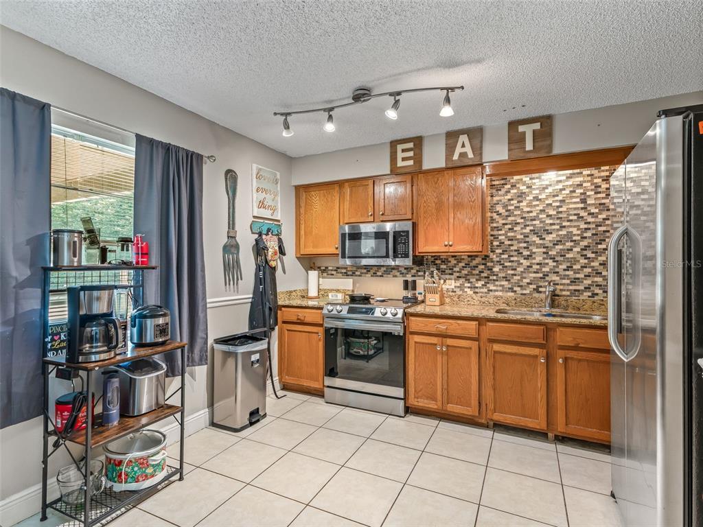911 Jacaranda Drive Lady Lake, FL 32159 - Photo 8 of 24 a kitchen with stainless steel appliances granite countertop a refrigerator and a stove top oven