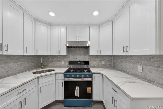 a kitchen with granite countertop white cabinets sink and stainless steel appliances