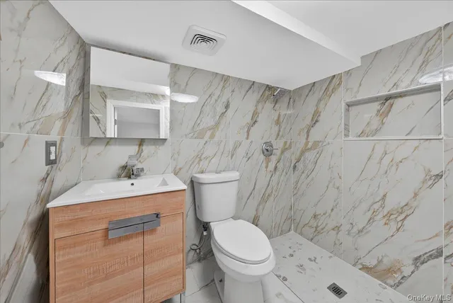 a bathroom with a granite countertop toilet sink and mirror