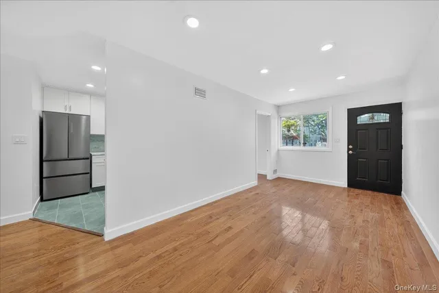 a view of an empty room with a window and wooden floor