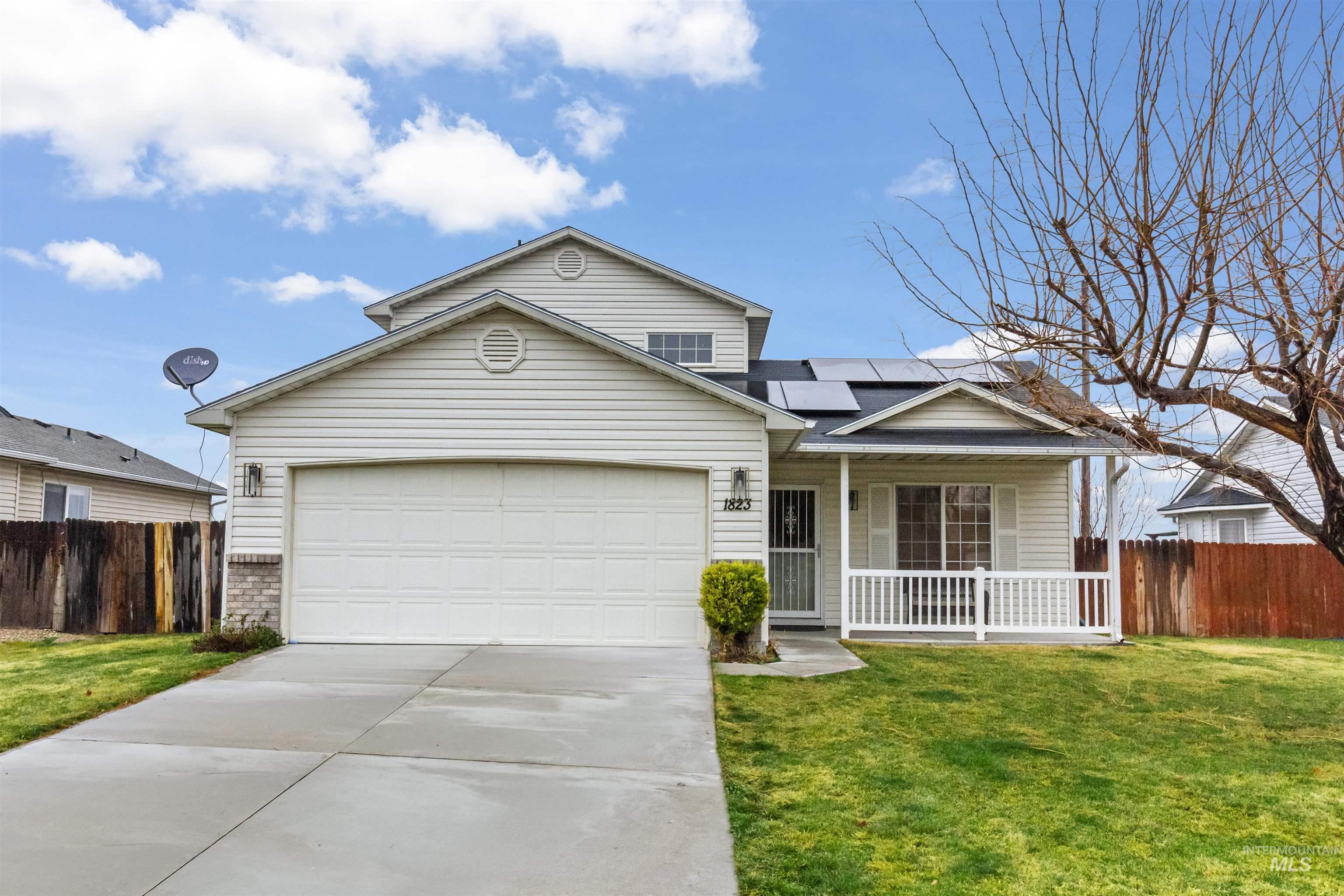 View of front of property featuring solar panels, covered porch, an attached garage, and concrete driveway